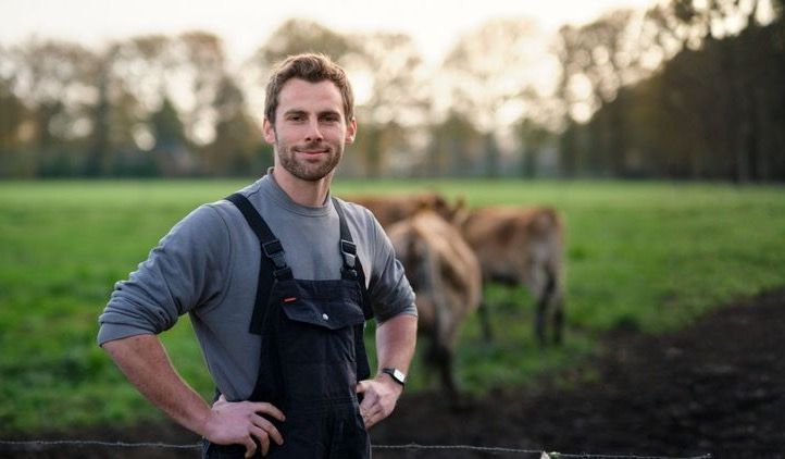 Agrarisch medewerker in werkkleding bij koeien